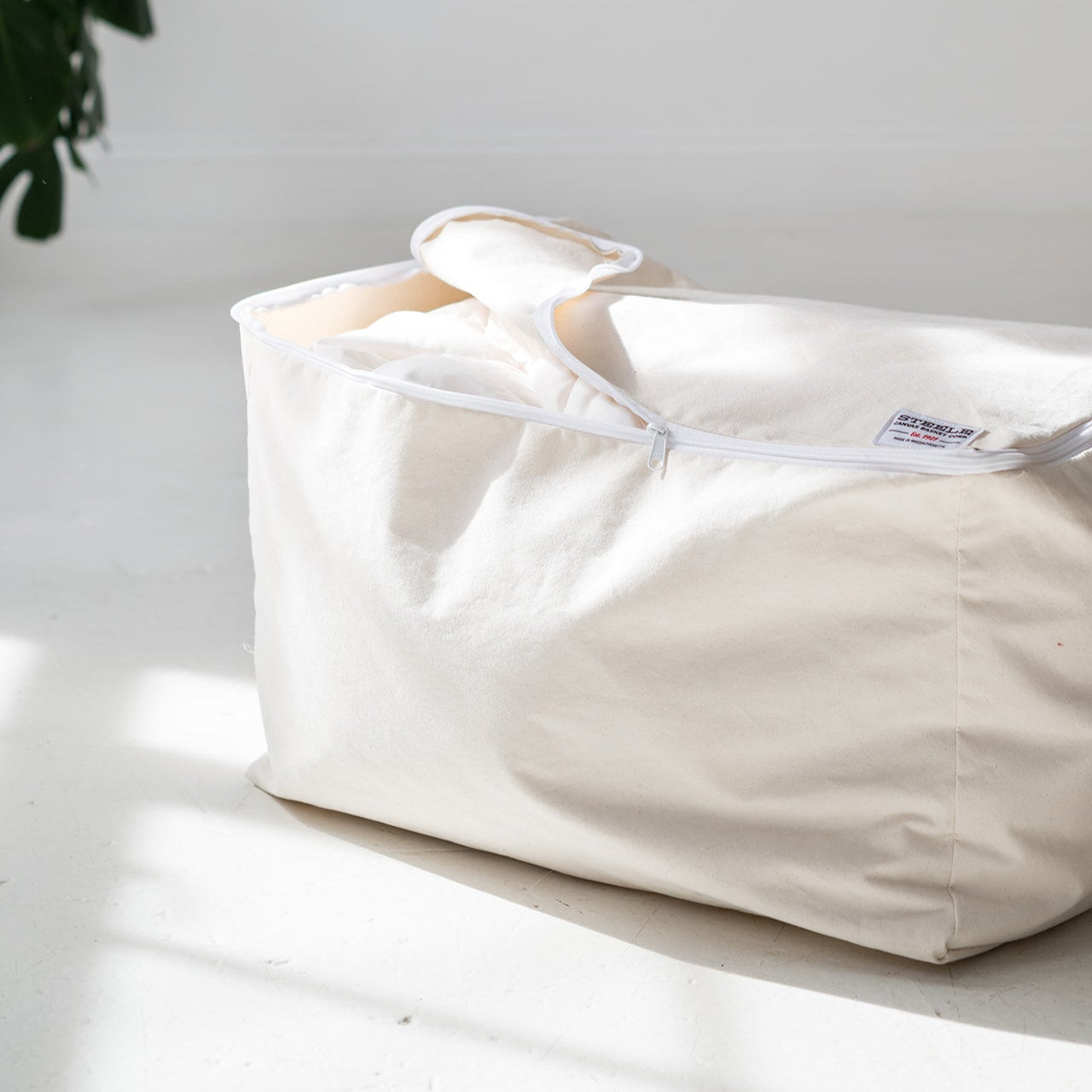 White fabric bag with a visible brand label on a light surface.