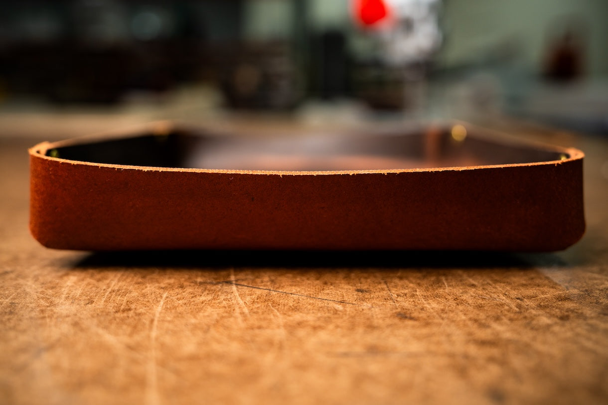 Brown leather tray on a wooden surface with a blurred background