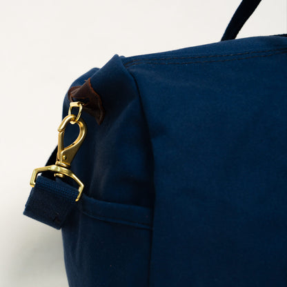 Close-up of a navy blue bag with a gold clasp on a white background