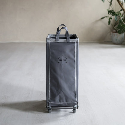 Gray rolling cart with 'STEELE' branding on a light surface with a plant in the background.