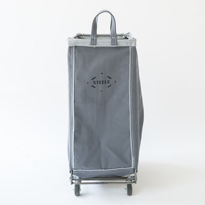 A gray fabric rolling storage bag with a top handle and wheels, featuring a black 'STEELE' logo printed on the front, set against a plain white background.