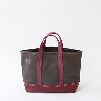 A canvas tote bag with a dark brown body, deep burgundy bottom panel, and matching burgundy handles, shown on a clean white background.