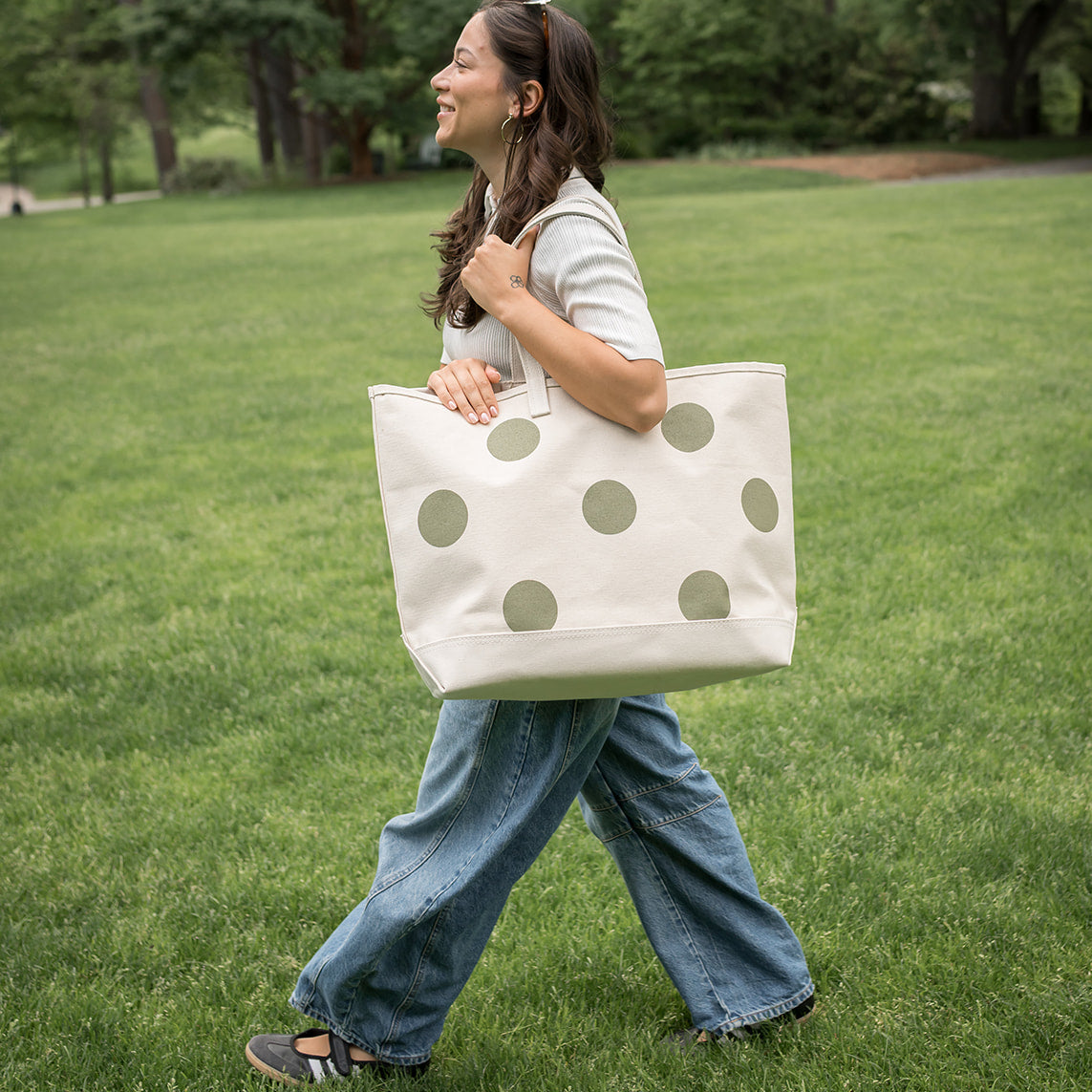 Woman walking outdoors with a polka dot tote bag