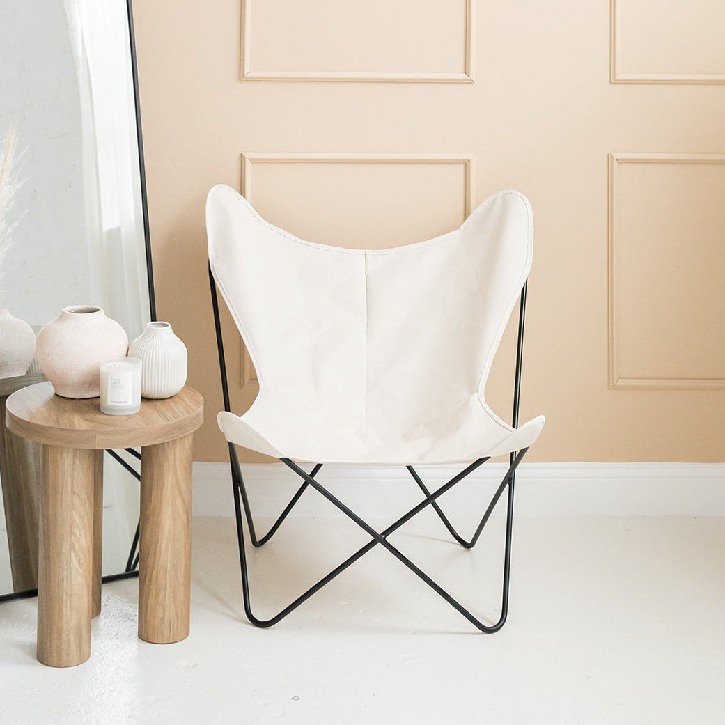 White chair with black metal frame in a room with a mirror and decorative items.