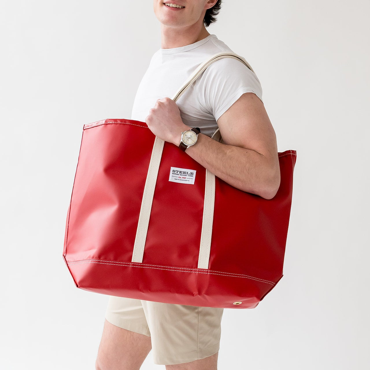 Person holding a red tote bag with a white background