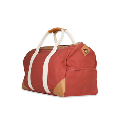Red duffel bag with white straps and brown accents on a white background