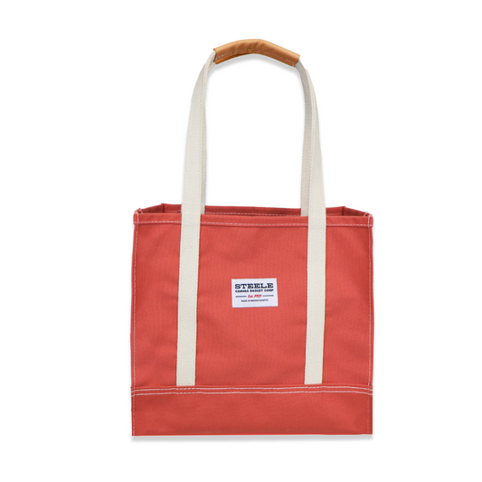 Red tote bag with white handle and label on a white background