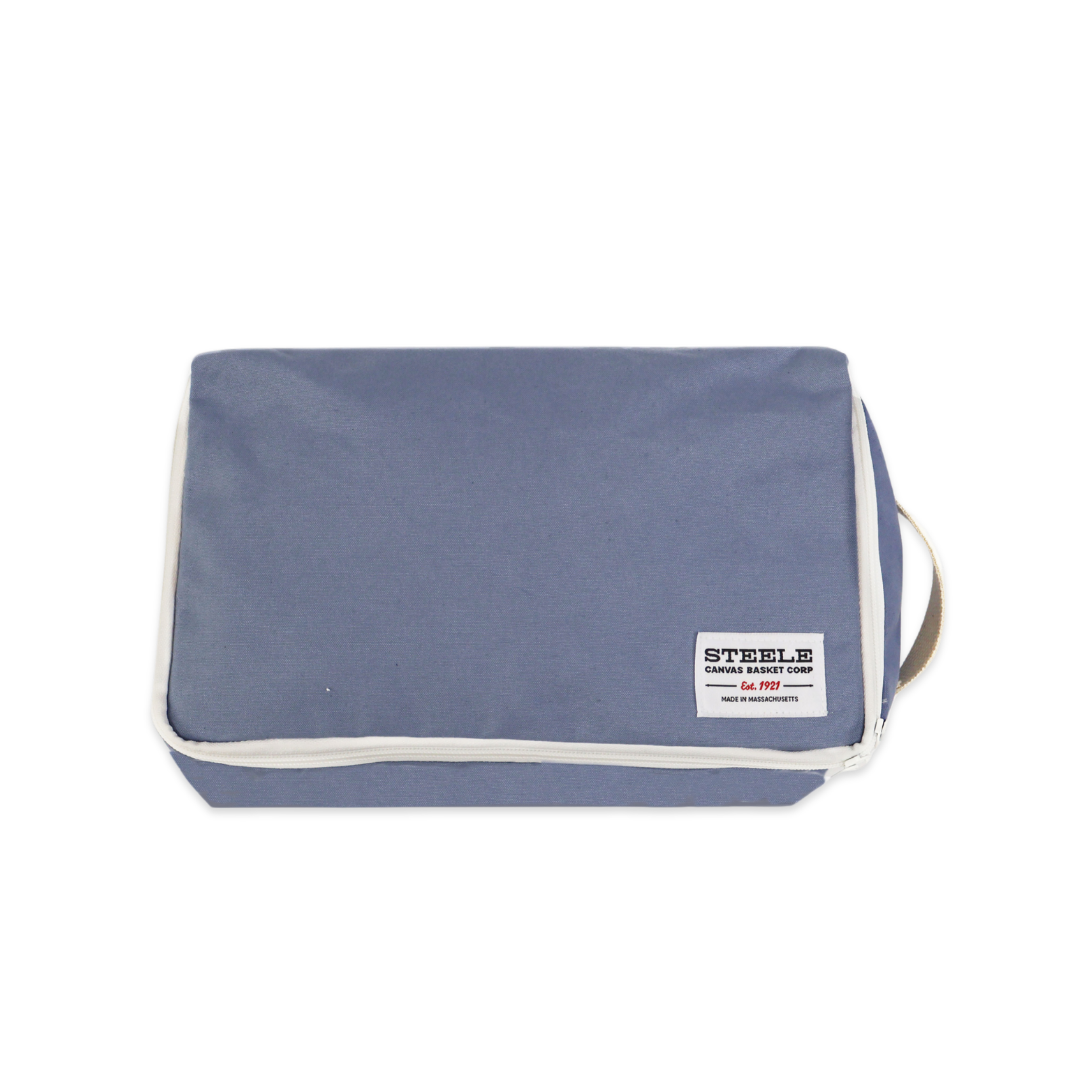 A slate blue zippered pouch with white piping and a white brand label reading STEELE, shown on a plain white background.