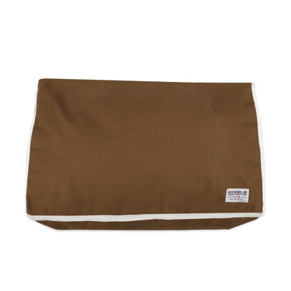 A brown canvas pouch or sleeve with white contrast piping along the edges and a small white brand label in the bottom right corner, shown against a plain white background.