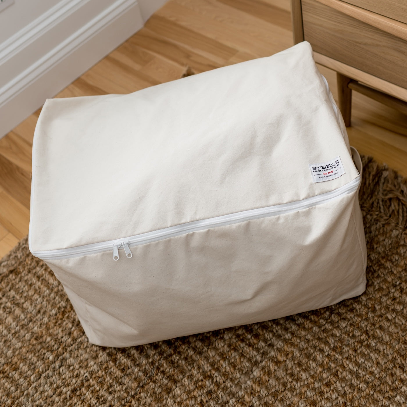 Beige storage bag with a zipper on a carpeted floor