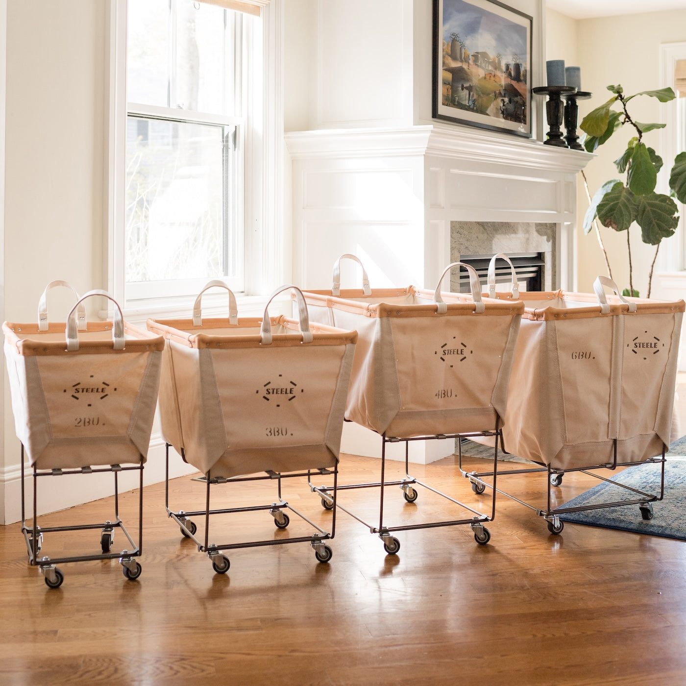 Set of canvas laundry carts with wheels in a room with a fireplace and window.