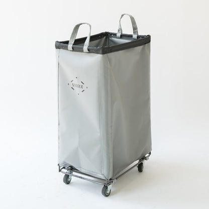 A light gray fabric laundry hamper with black trim, dual top handles, and a wheeled base, photographed against a plain white studio background.