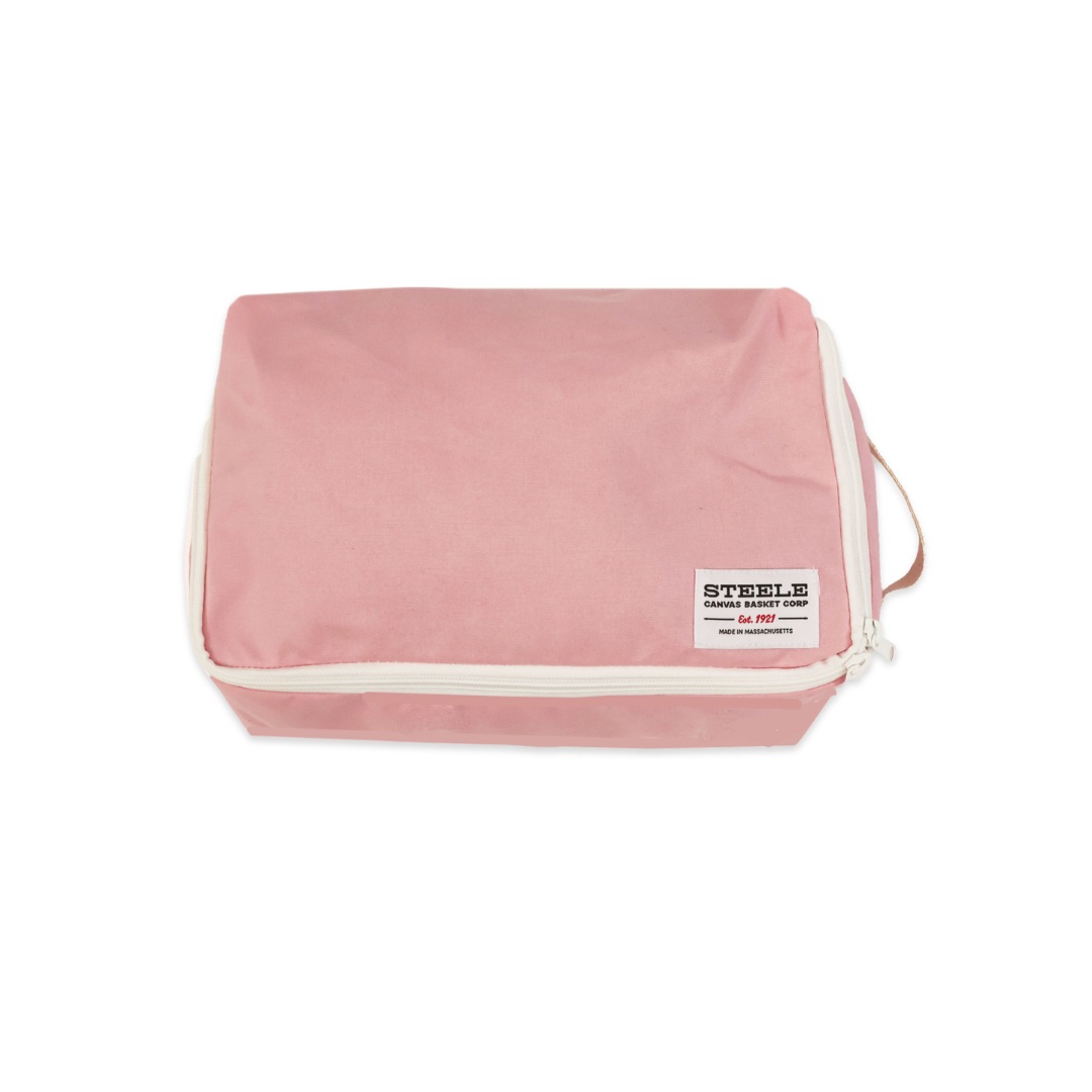 A pink zippered toiletry bag with cream-colored piping and a white brand label reading 'STEELE Canvas Basket Corp' on a plain white background.