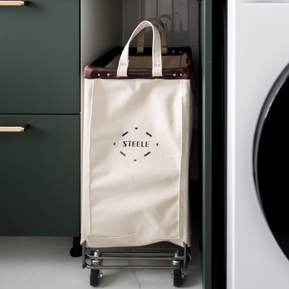 Beige laundry cart with 'STEELE' logo in a laundry room setting